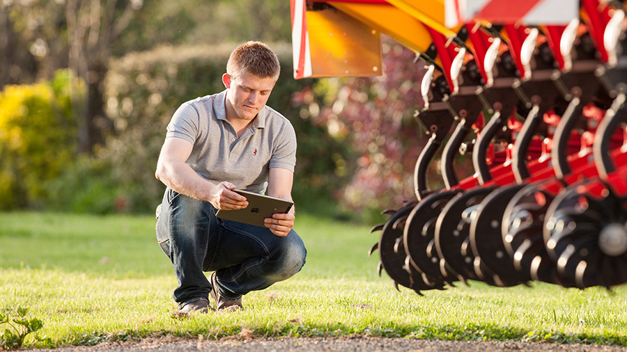 Farmer using iPad for searching information beside Väderstad Tempo